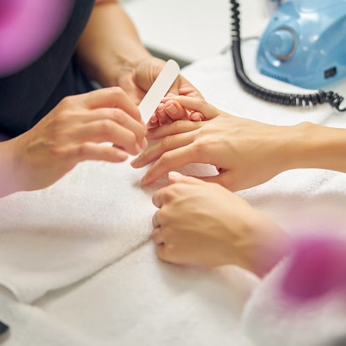 A woman having her nails filed by professional in a salon.